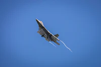 a jet flying through a clear blue sky